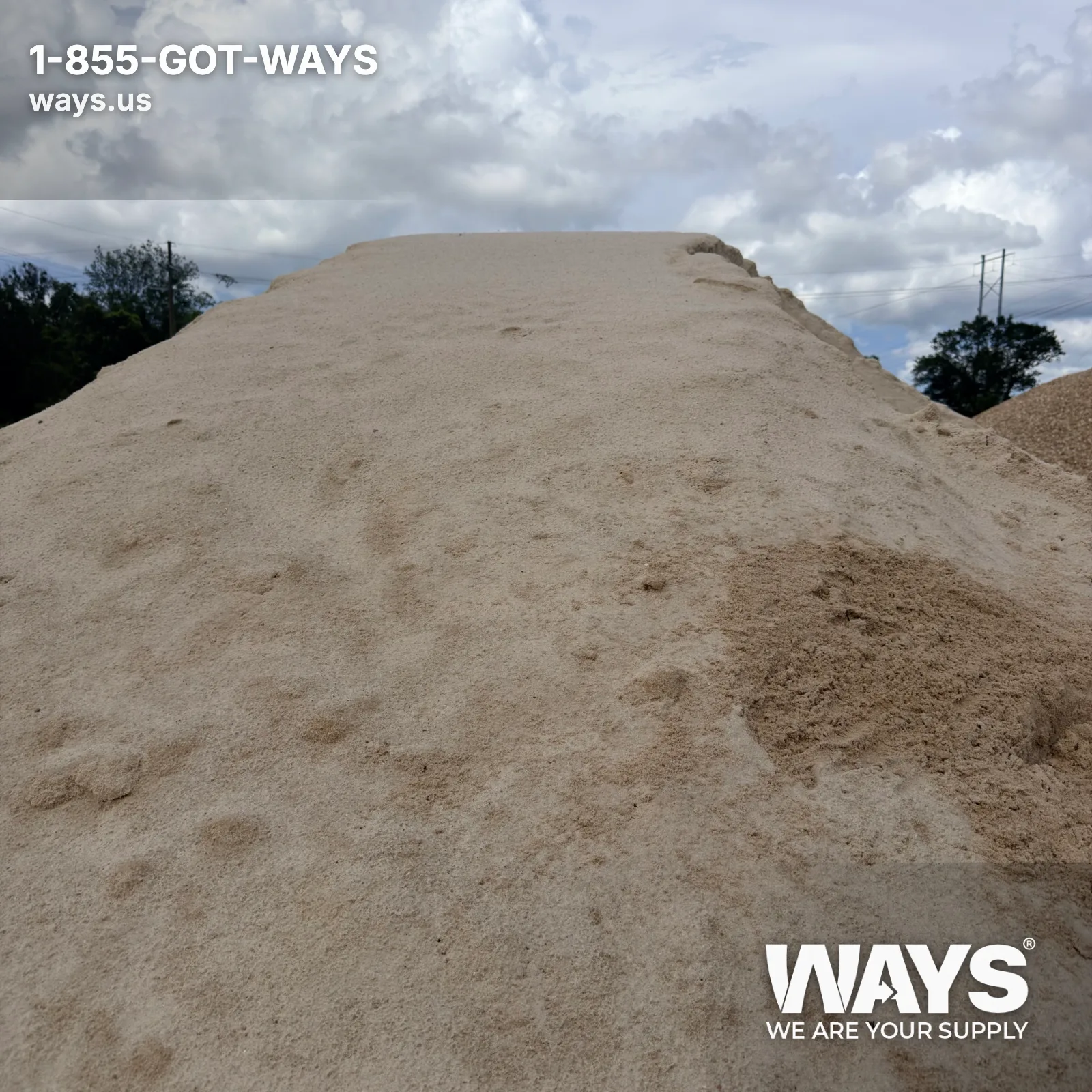 Hand holding a scoop of fine masonry sand over a large pile